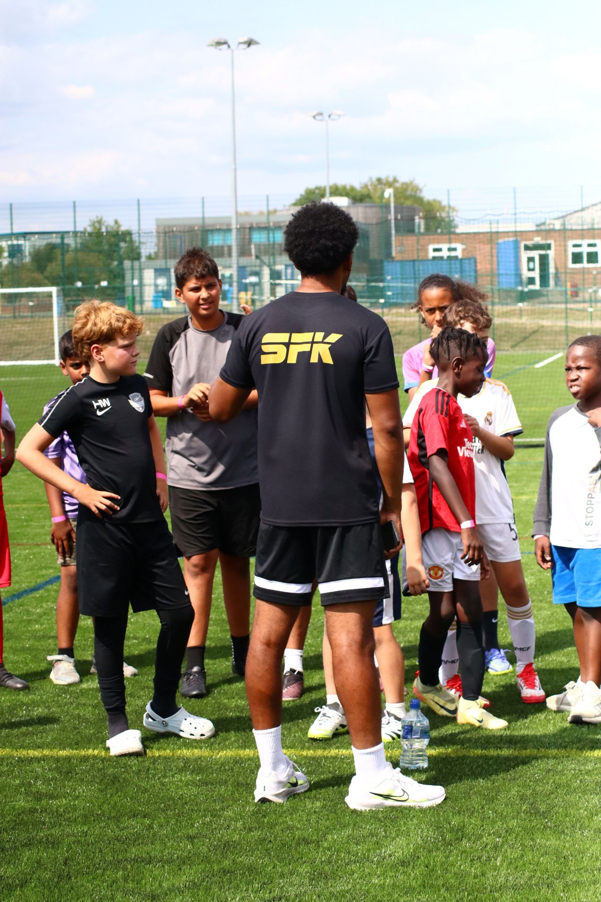 An SFK coach with children on an outdoor sports pitch