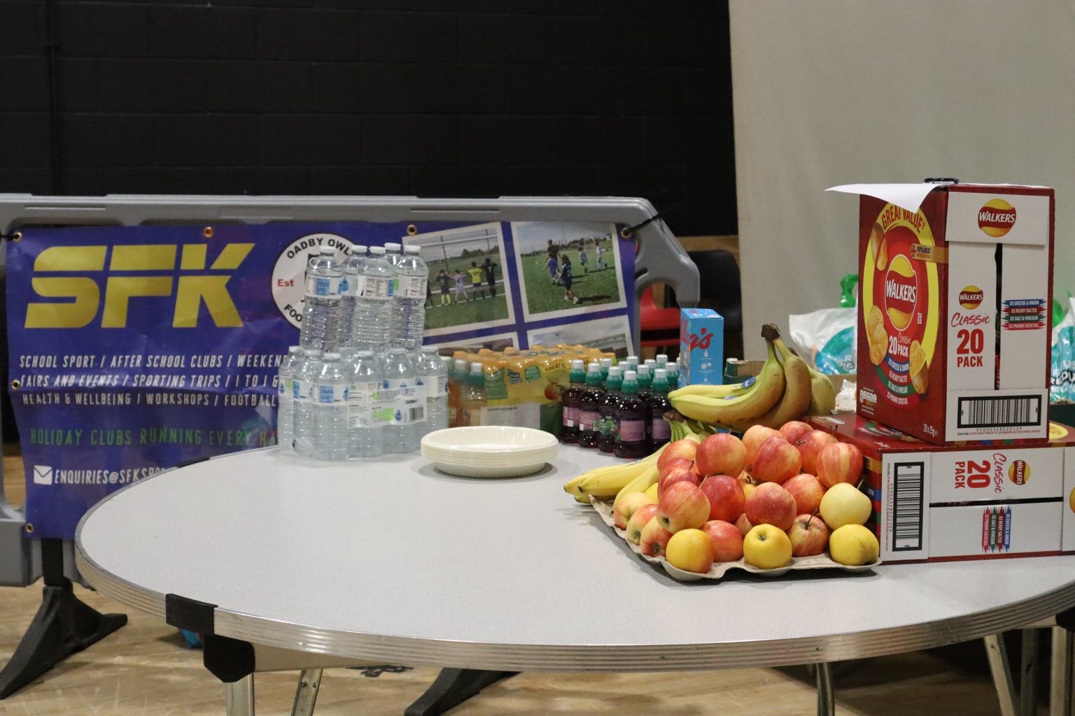 Fruit and drinks arranged beside an SFK banner